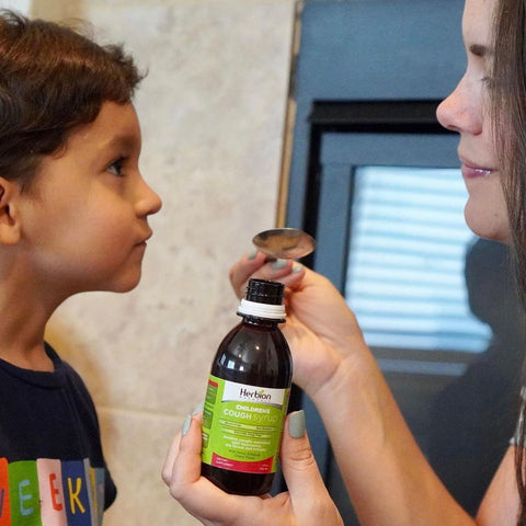 A mom giving Herbion Children's Cough Syrup to her child